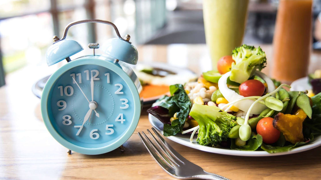 Intermittent fasting represented by an alarm clock and food.