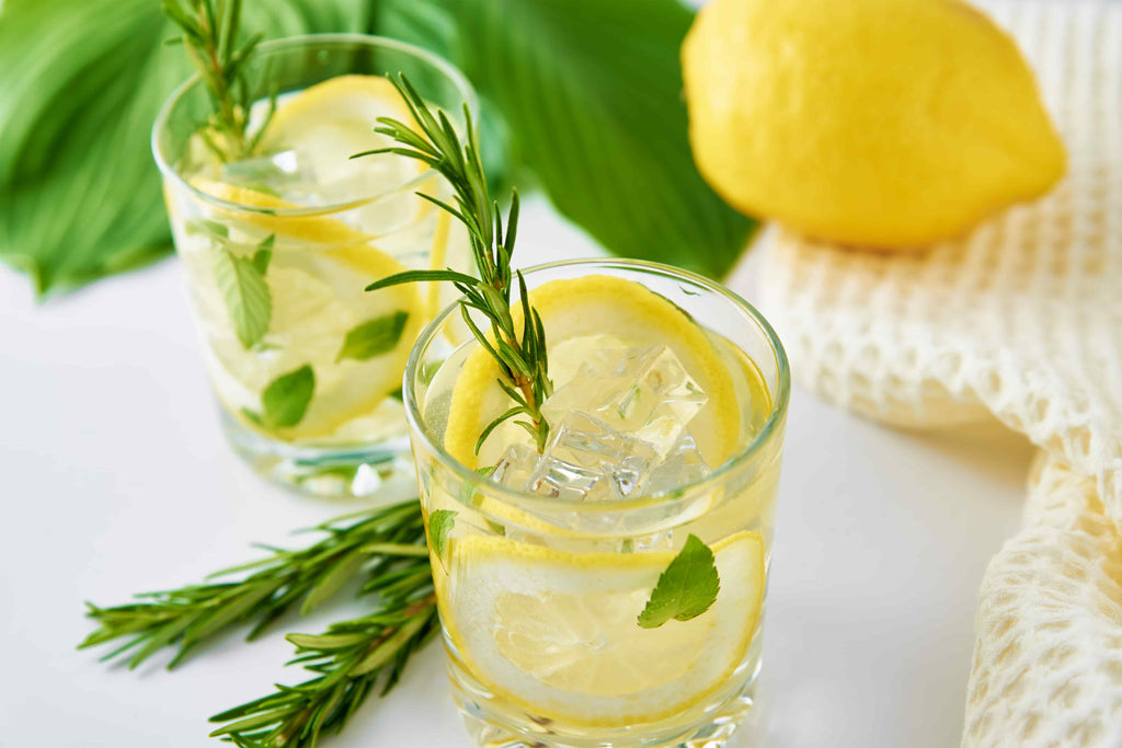 Glasses of water with lemon slices, a whole lemon on the side. 