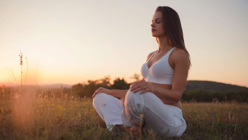 A woman practicing mindfulness meditation outdoors.