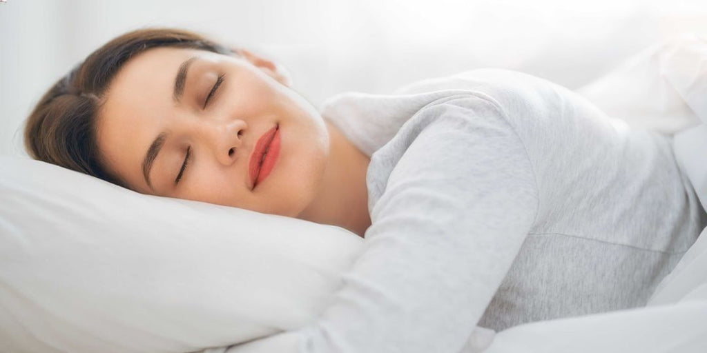 A woman sleeping at night on a white bed.