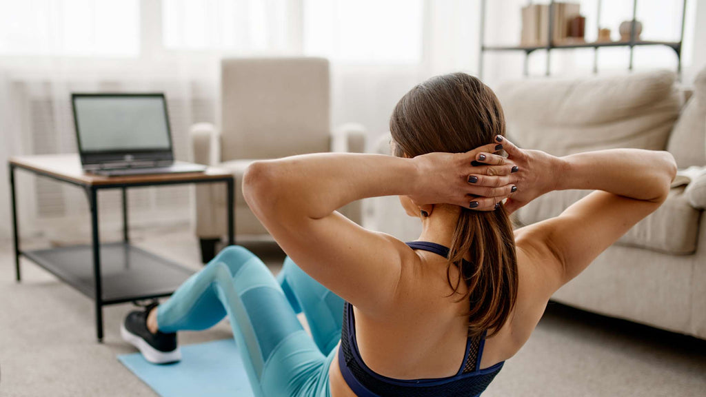 A woman exercising and attending a virtual fitness class. 