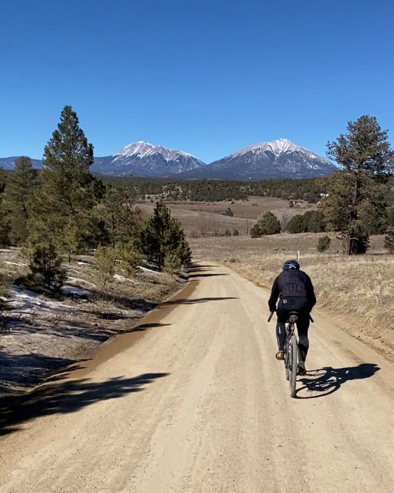 bicycle rider on a dirt road with mountains in the background