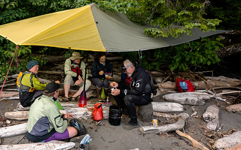 Ikkatsu Project huddled from rain using a tarp supported by a Werner Paddle to stay dry.