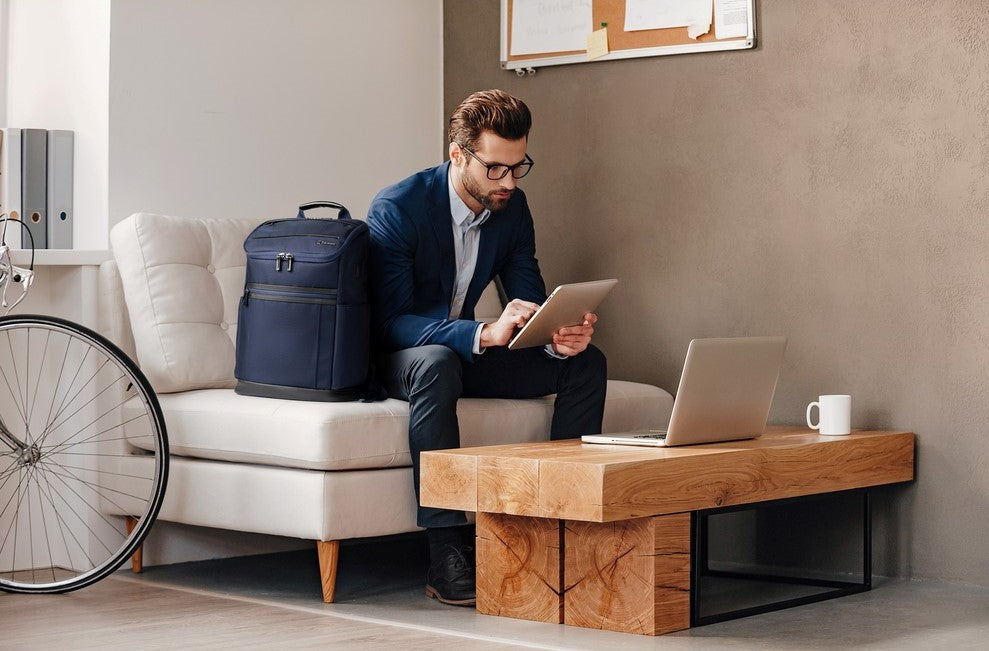 Homme assis à une table avec son ordinateur portable et son sac à dos
