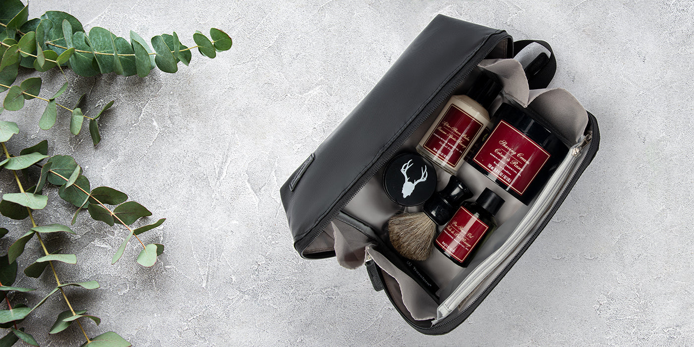 Trousse de toilette posée sur un comptoir en marbre avec de l'eucalyptus