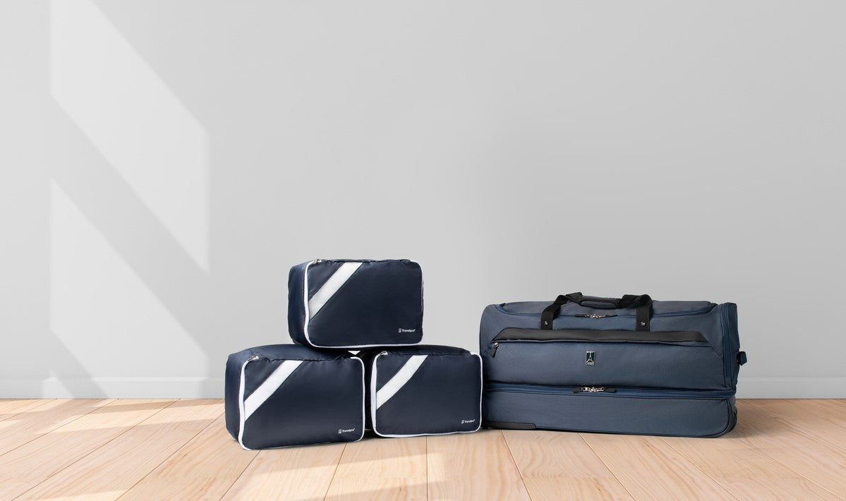 Duffel bag laying on the floor with 3 packing cubes next to it