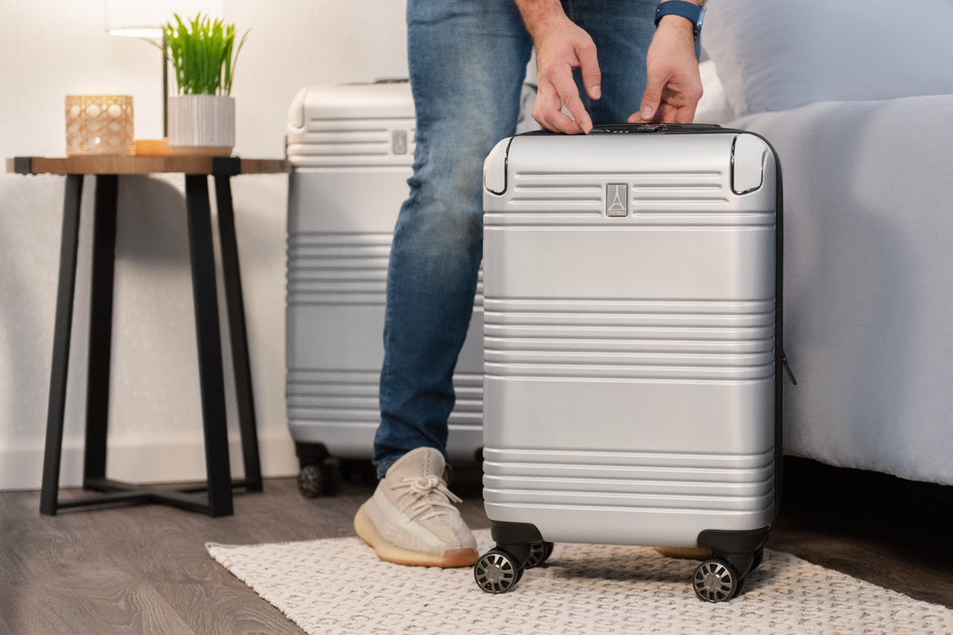 Man locking suitcase next to bed 