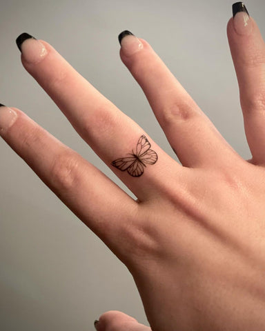 Tatuaje minimalista de mariposa para dedo.