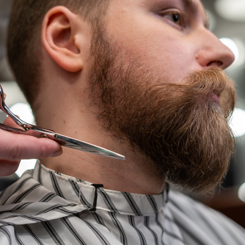 Hombre en barbería cortando su barba