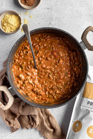 pot of chili with spices on gray background