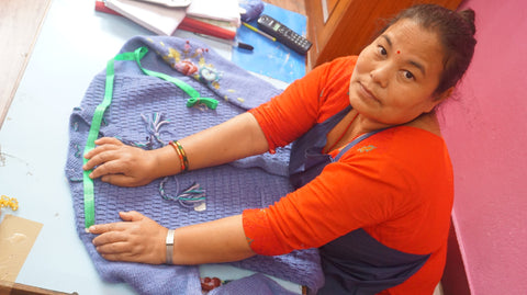Nepalese Women Leaning Forward on Blue Knitted Sweatshirt with a Tape Measure