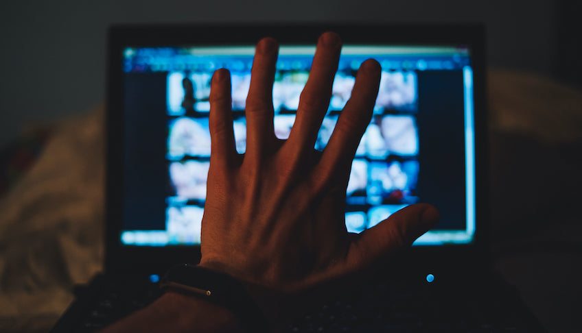 Hand vor Bildschirm mit verschwommenen pornografischen Inhalten