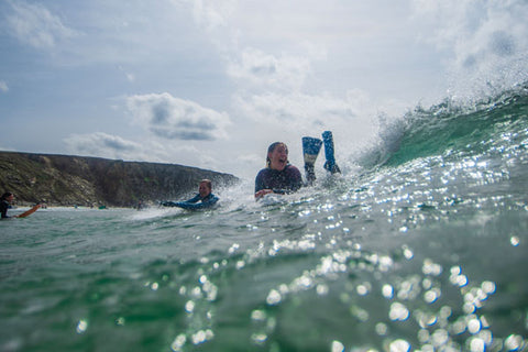 Two people surfing a wave on bellyboards