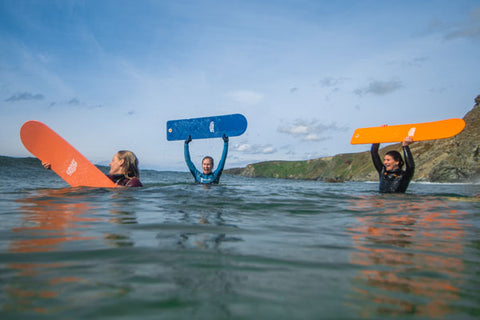 Three people in the sea holding bellyboards