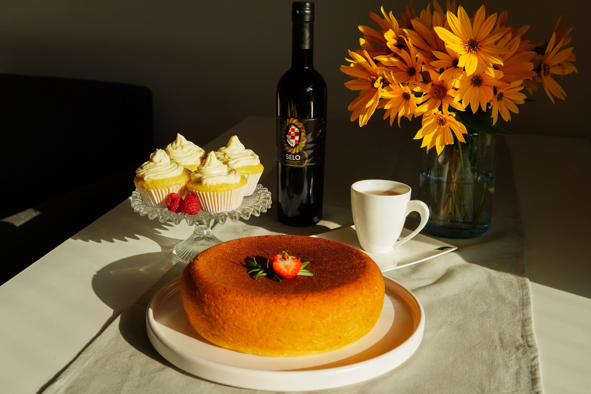 Sumptuous shortcake adorned with cupcakes and a bottle of Selo olive oil, a sweet and savory indulgence.