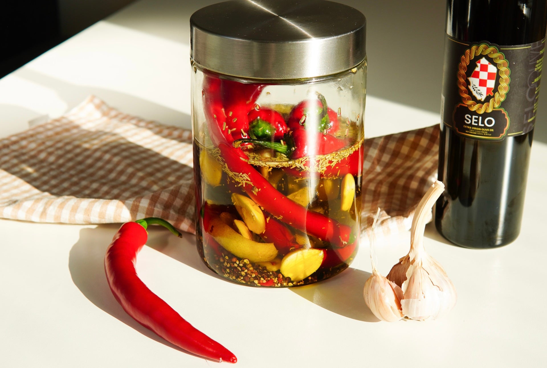 A jar of garlic and pepper-infused Selo Croatian olive oil, a flavorful culinary delight.
