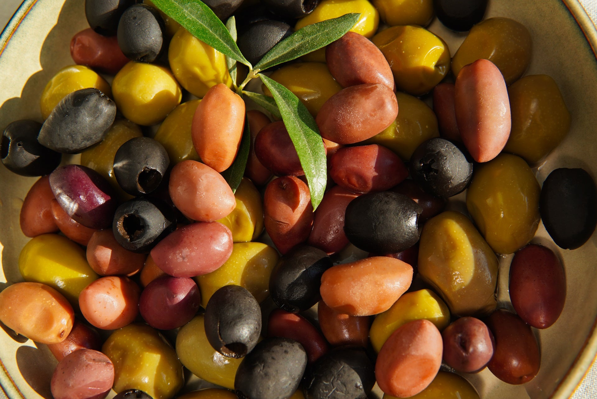 Green and black olives on a table - A spread of green and black olives arranged neatly on a table surface.