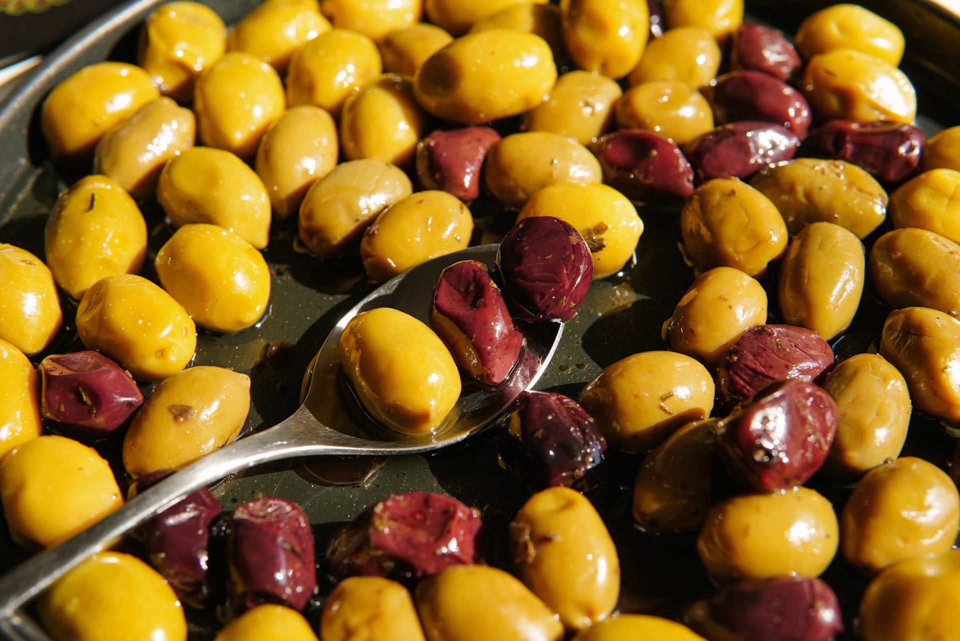 Green and black olives on a table - A spread of green and red olives arranged neatly on a table surface.