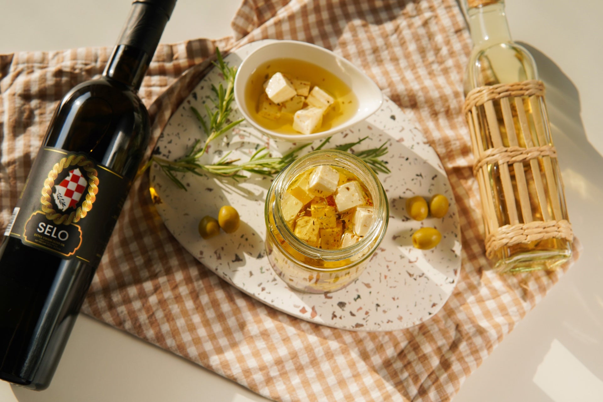 Preserved feta cheese cubes in a clear jar, bathed in a lustrous olive oil.