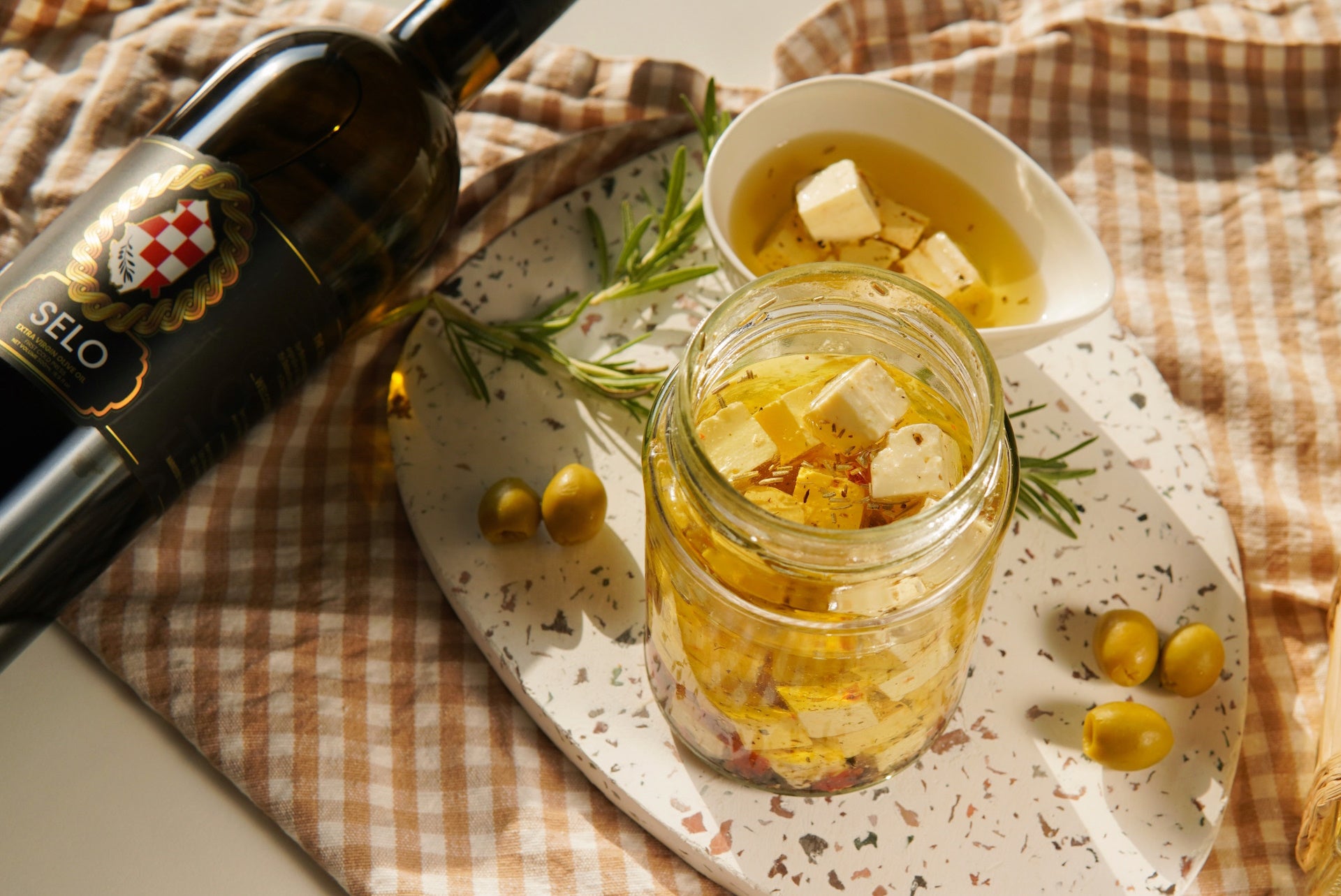 Glass jar filled with cubed feta cheese submerged in glistening olive oil.