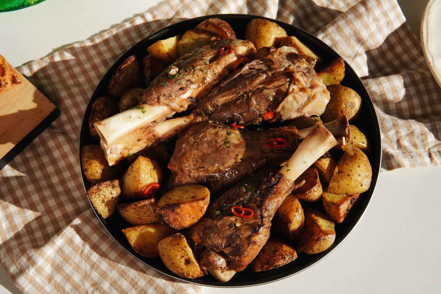 A traditional Croatian lamb peka roast cooked with Selo Olive Oil under a dome-shaped bell with burning embers, resulting in succulent, tender meat accompanied by potatoes.