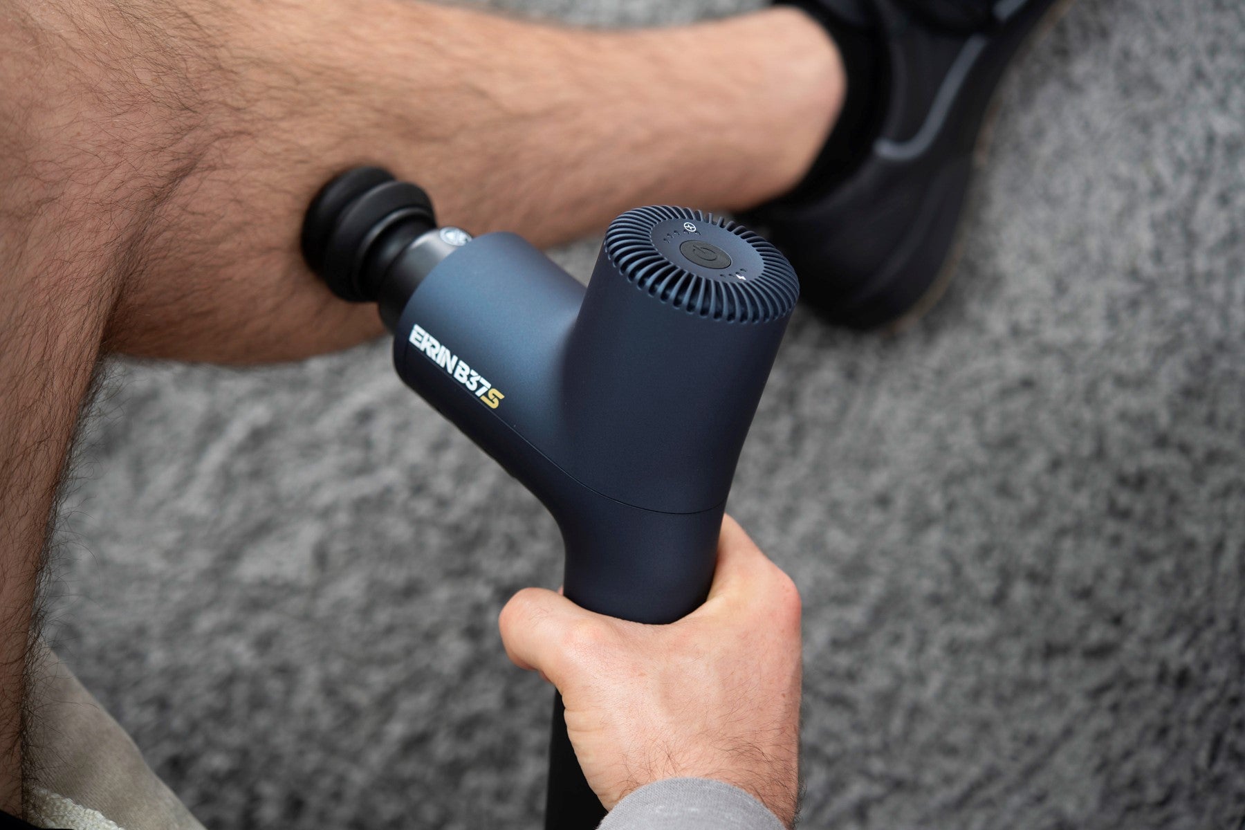 Man massaging leg with massage percussion device after workout.