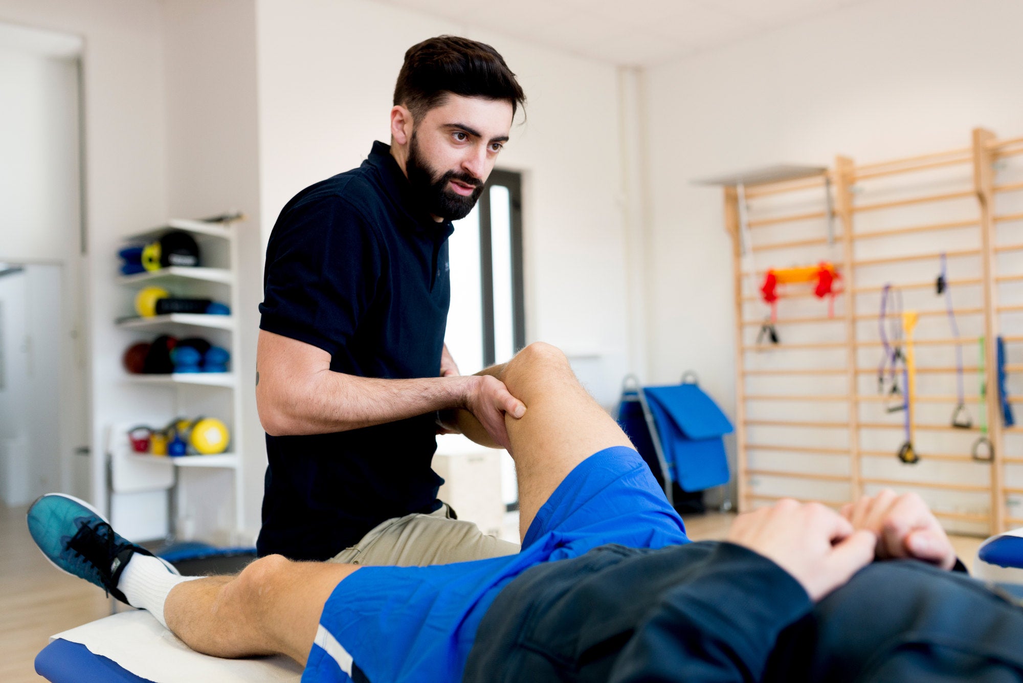 Physical trainer performing sports massage on athlete