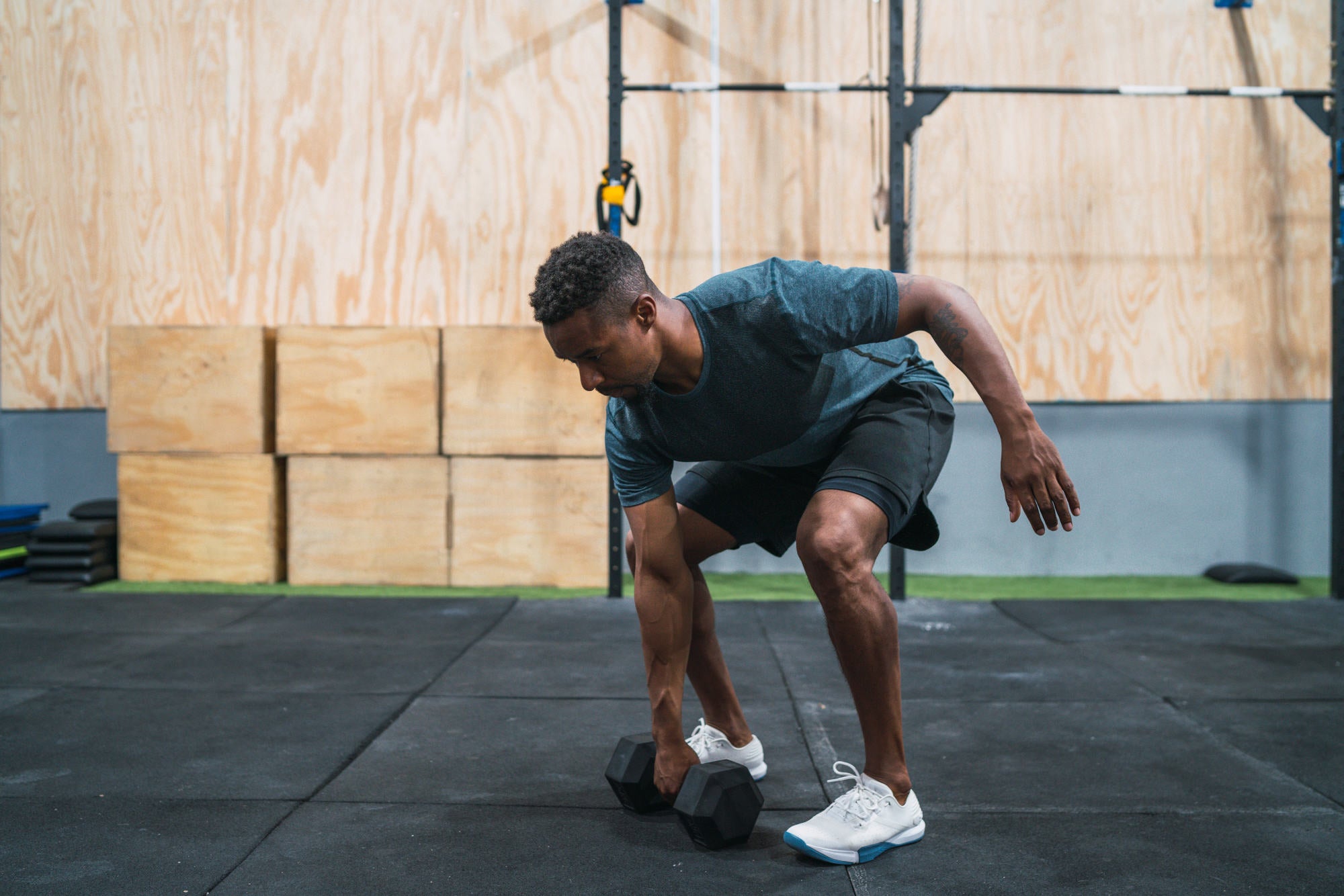 Portrait of young crossfit athlete doing exercise with dumbbell at the gym. Crossfit, sport and healthy lifestyle concept.