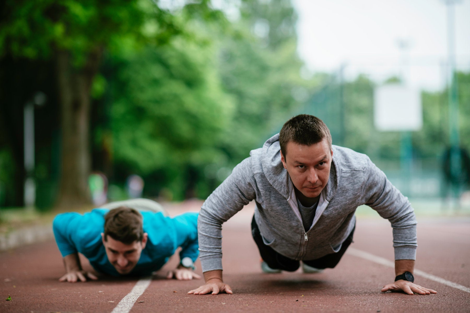 Young men exercising on a race track. Two young friends training outdoors.