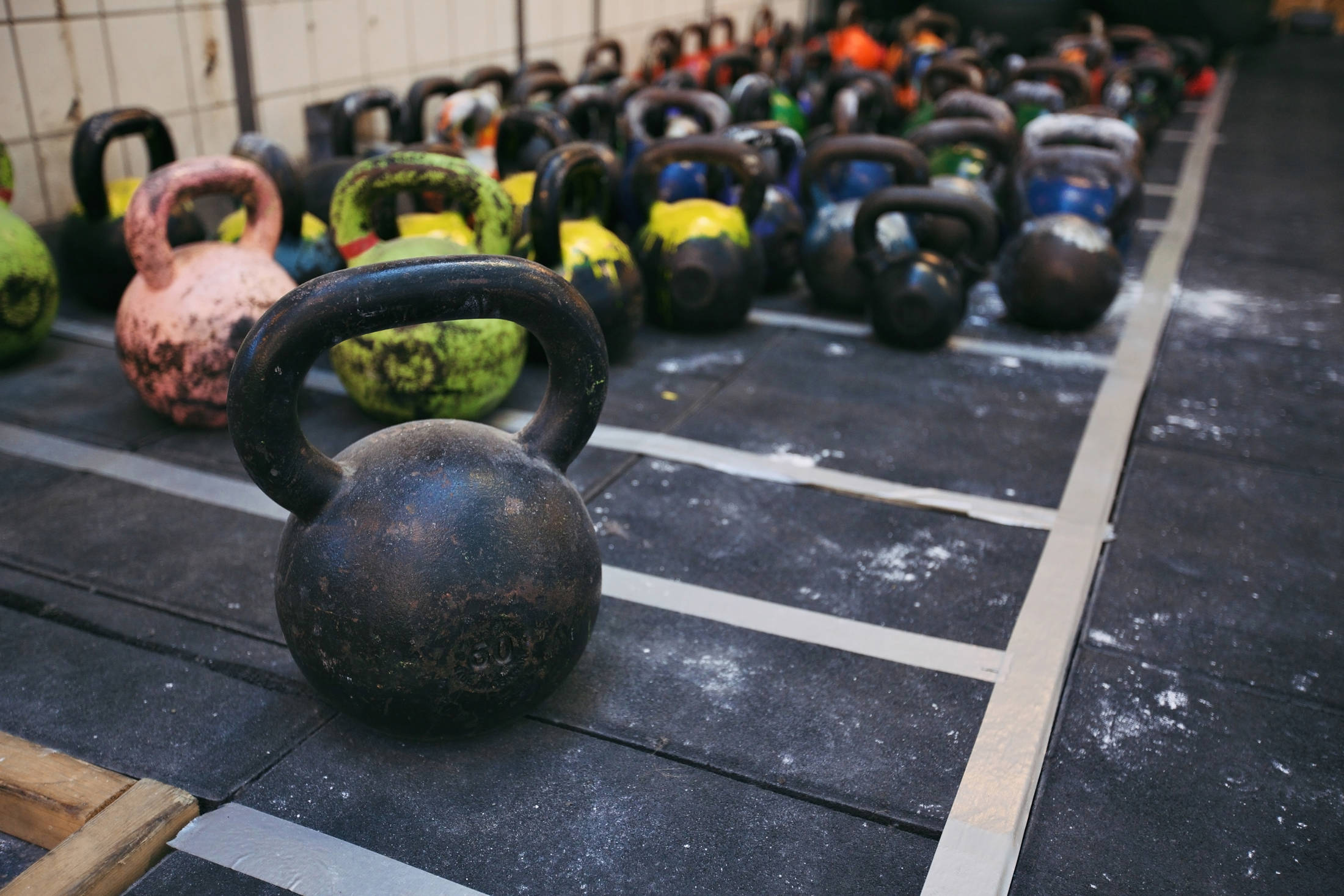 Different sizes of kettlebells weights lying on gym floor. Equipment commonly used for crossfit training at fitness club