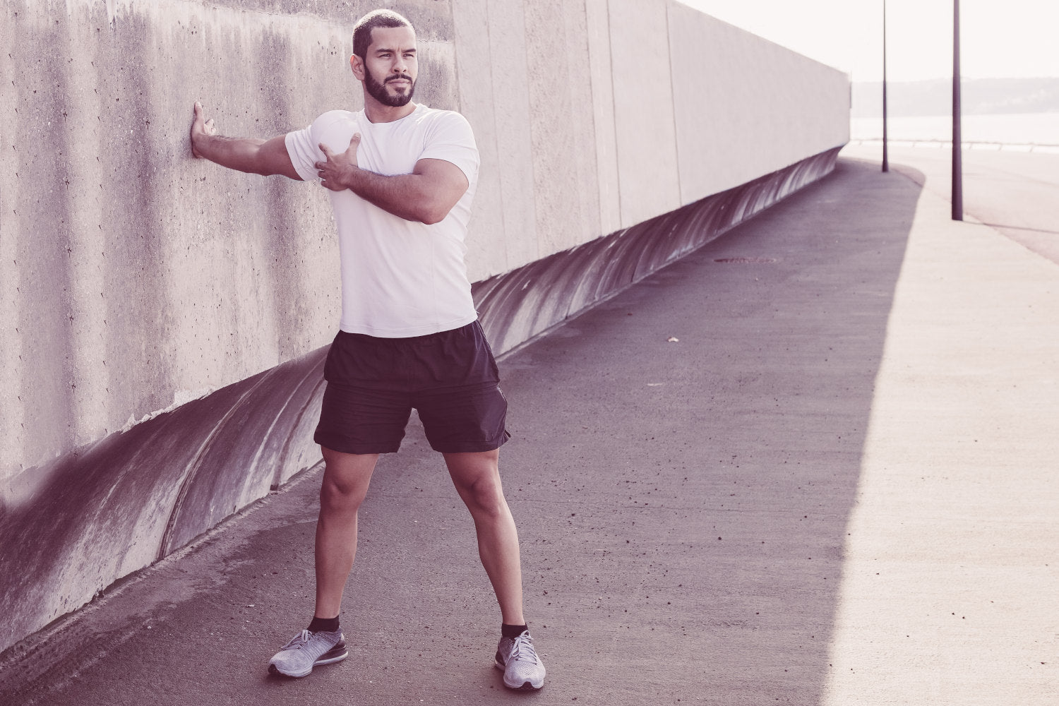 Man using a concrete wall to stretch shoulder