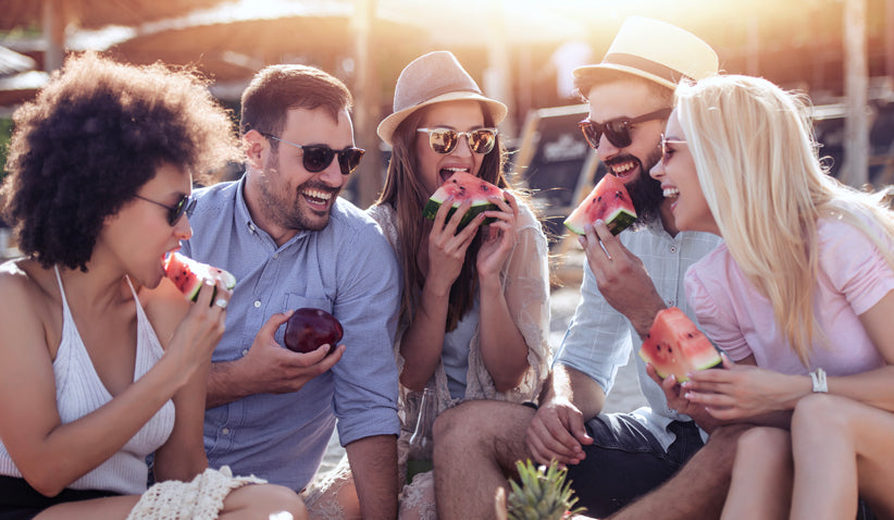 a group of people laughing while enjoying watermelon
