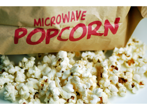 Bag of microwave popcorn sitting on top of popped popcorn.