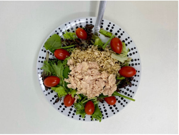 mixed greens, tomatoes, brown rice and tuna in a bowl.