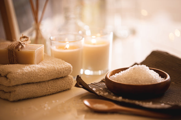 Bath salts, candles, and other spa related items on a granite countertop