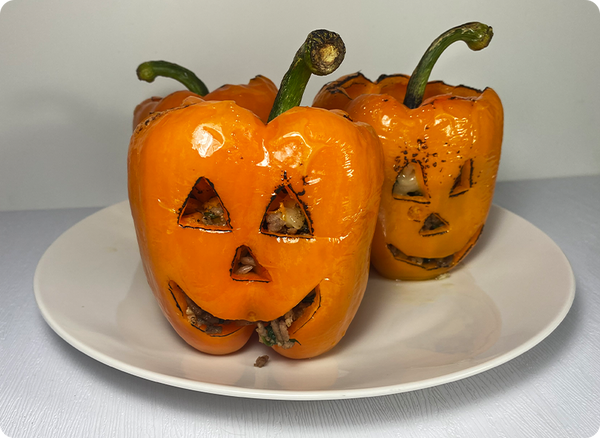 Stuffed orange peppers that are cut to look like like jack-o-lanterns