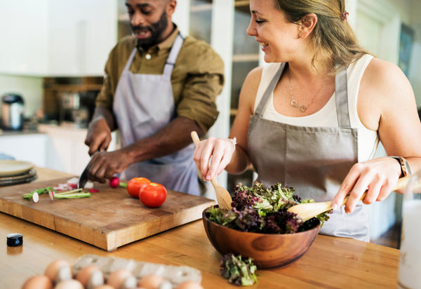 Couple cooking together and preparing a salad made with fresh lettuce and vegetables