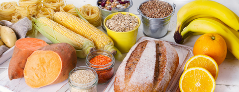 table with bread, corn, sweet potatoes, rice, beans, an oranges, and bananas