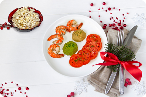 Plate of shrimp, hummus, cherry tomatoes, and guacamole next to a bowl of popcorn.  The popcorn is 2 cups and is topped with parmesan cheese