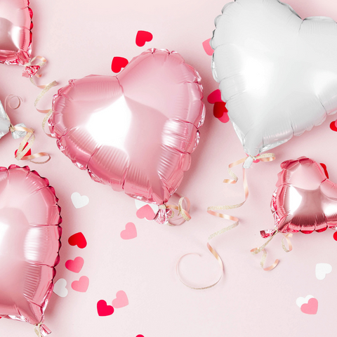 pink and white mylar heart balloons on a pink backdrop with red, white, and pink heart confetti