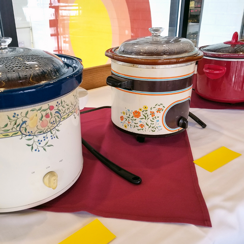 three crock pots on a long table at a chili cook off