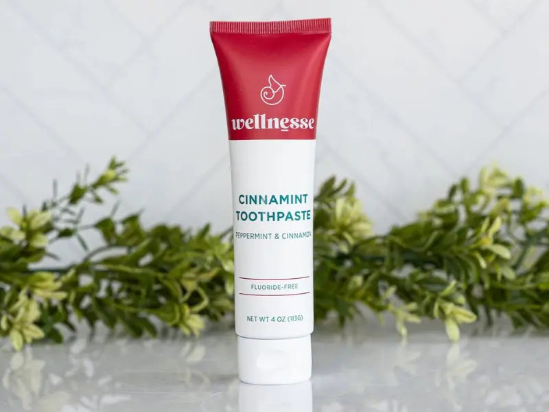 Remineralizing fluoride-free toothpaste in a cinnamint flavor standing upright with greenery background.