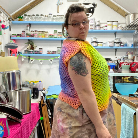 a photo of me standing side onto the camera in my dye shed, making a pouting model face. I have on my crochet square top and you can see here how the yarn fades from lime green through yellow up to pink on the front, then from the pink through to the purple onto the back making two different coloured pieces but with a continuous fade through the colours from front middle to back middle