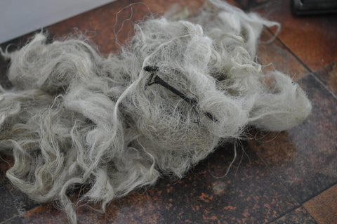 a clump of fleece on a brown worktop, you can see a stick stuck in it and a bit of a matt