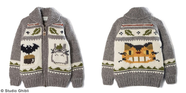 the same cardigan side by side, front and back view, its a super chunky cardigan with grey sleeves that then has a big cat bus face on the back and on the front a wee totoro on one side of the zip and an acorn and a bat on the other. near the neck there are some leaf motifs