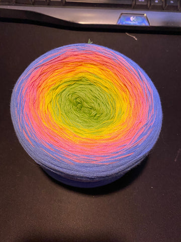 a cake of yarn it is a cotton yarn and you can kind of see that its made up of about 4 strands of thinner yarn together. the colour starts at a lime green in the middle, fades through to yellow, then pink and ends with a lilac purple colour