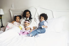 Sleep well to overcome anxiety: mother playing with kids on her bed