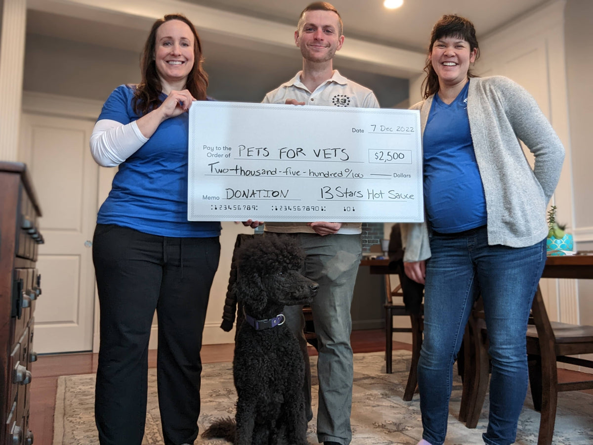 Sean from 13 Stars Hot Sauce holding a check that says Pets for Vets on it