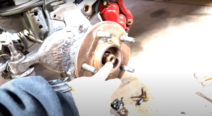 Brake caliper hanging near wheel hub after being removed