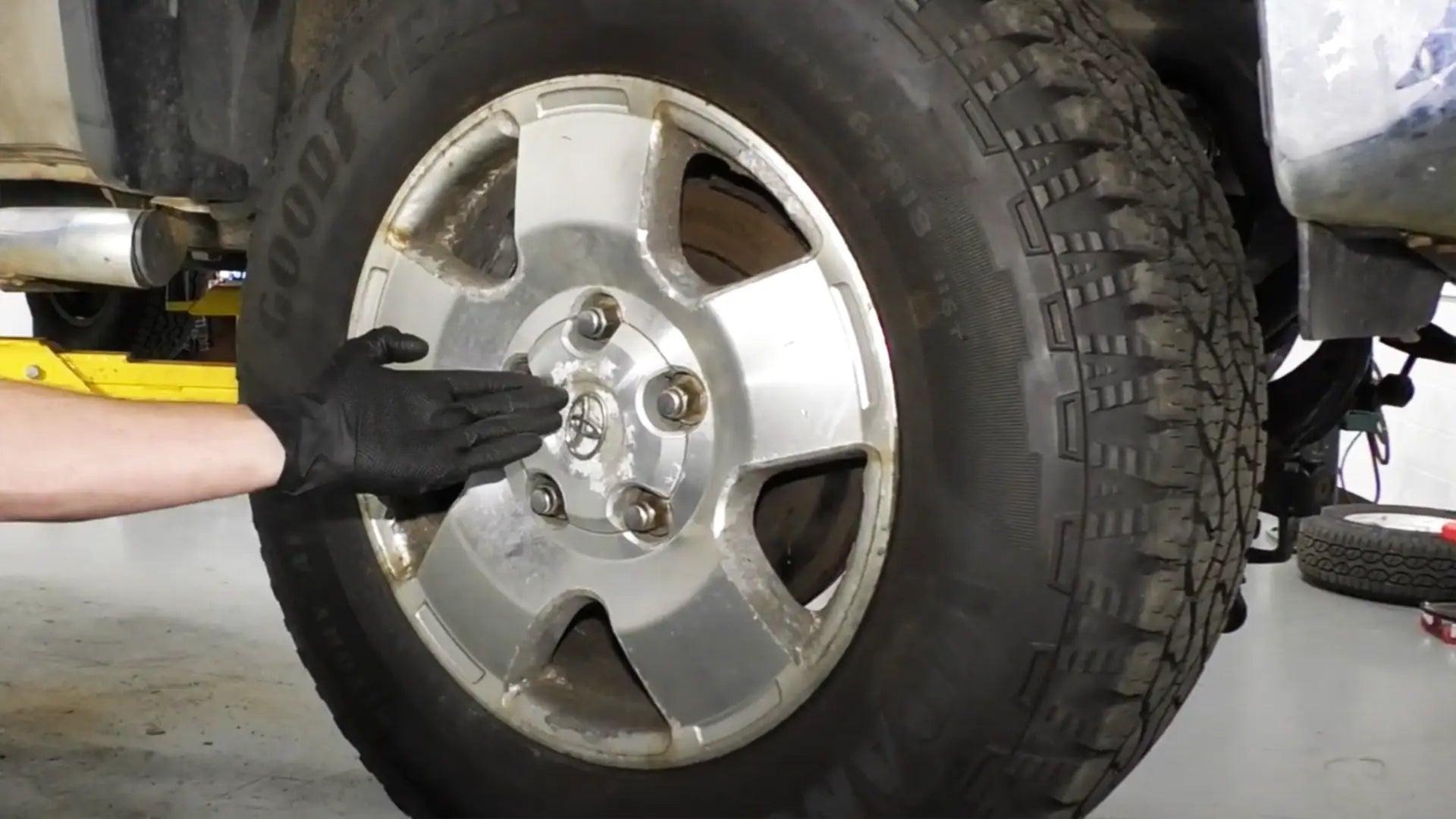 Gloved hand pointing to raised wheel for Toyota Tundra